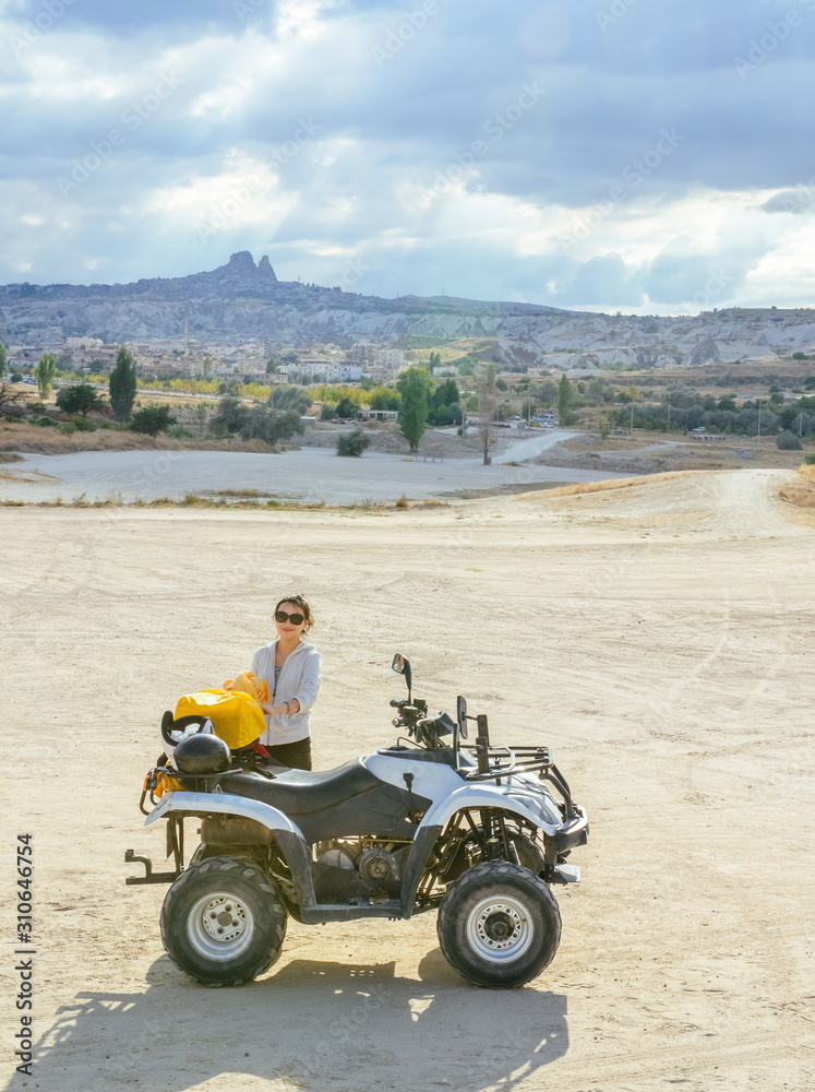 Asian girl making up bags by an ATV in Cappadocia's valley