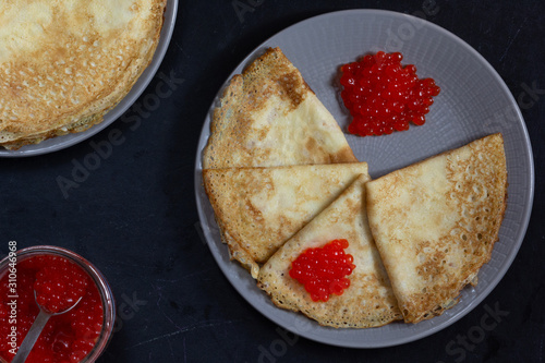 Blini triangles or crepes with red caviar on the plate with jar photo