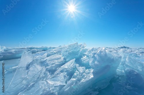 The bright sun over an endless field of ice hummocks. Cold winter landscape of the frozen Baikal Lake. Natural background