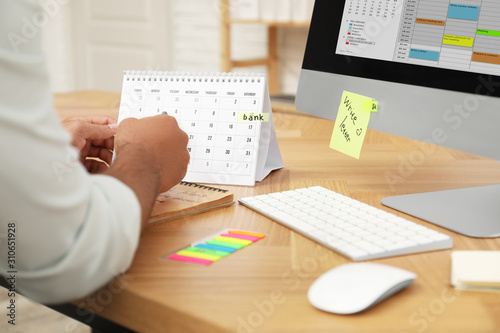 Man working with calendar at table in office, closeup