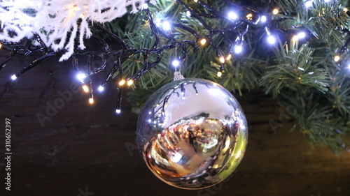 Christmas decoration, ball hanging on green fir tree. Branch with shiny globe. Red & white colors. Blur on background texture, lights for xmas. Holiday atmosphere, new year seasonal design ornament. 