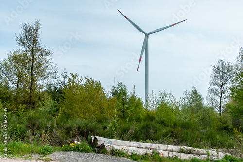 Windrad mit Wad und gerodeten Holzstämmen im Vordergund