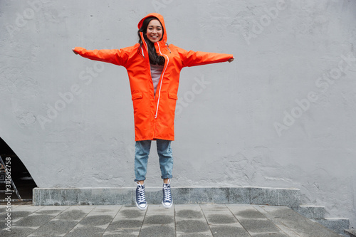 Attractive smiling young asian woman wearing raincoat
