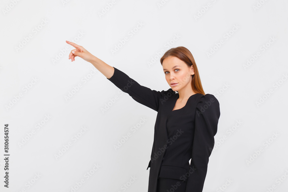 elegance girl on white background. Young serious woman in black dress pointing finger to the side elegance girl on white background. Young serious woman in black dress pointing finger to the side