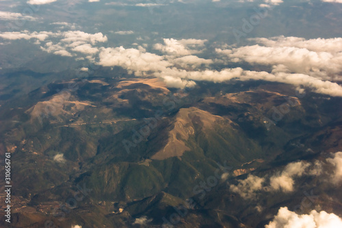 View from airplane window at mountains and white clouds flying above Montenegro. Aerial perspective. Aerial view of mountain landscape from an airplane window.