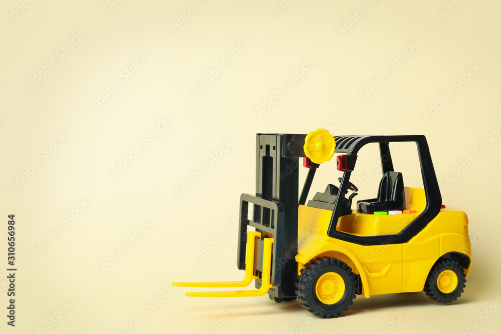 Toy forklift on beige background, space for text. Logistics and wholesale concept Toy forklift on beige background, space for text. Logistics and wholesale concept