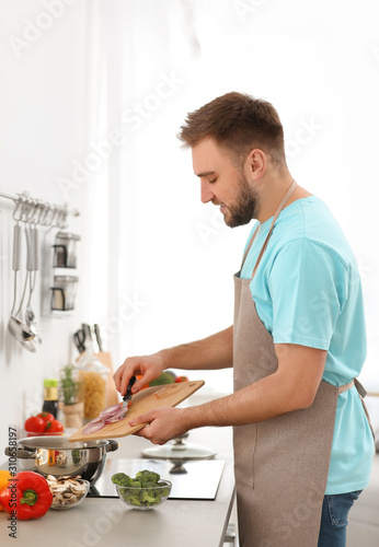 Young man cooking delicious vegetable soup in kitchen