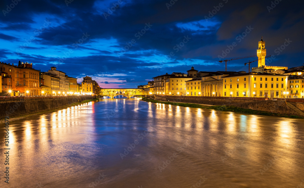 Panoramic night view of famous Ponte Vecchio over Arno River in Florence, Italy.