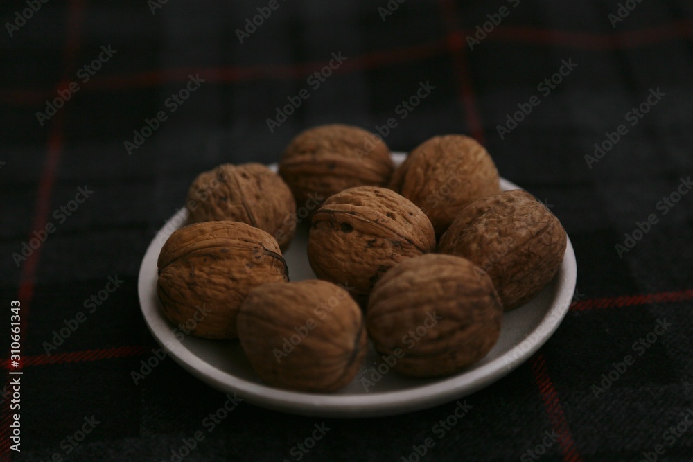Inshell walnuts on a plate against a dark background. Inshell walnuts on a plate against a dark background.