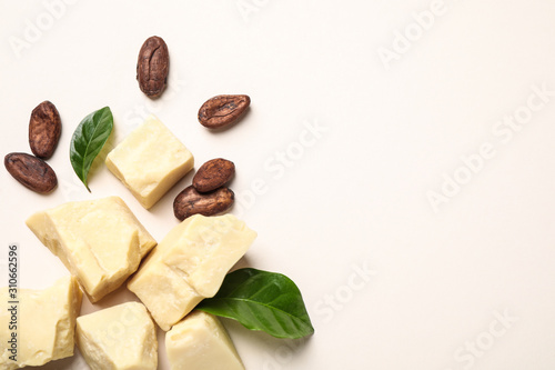 Organic cocoa butter and beans on beige background, flat lay. Space for text