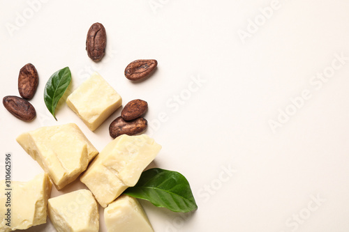 Organic cocoa butter and beans on beige background, flat lay. Space for text photo