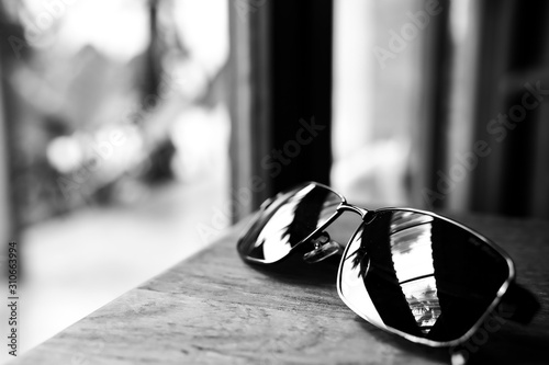 Single simple sun glasses on the wooden table with copy space, black and white color