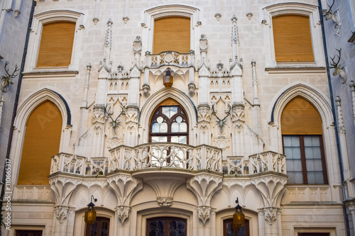 Balcony with curly railings and deer heads on stone wall of an old castle and window with shutters © Евгений Дубасов