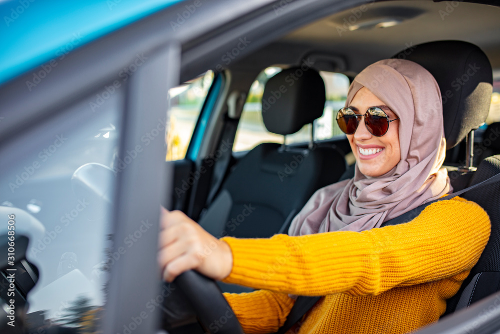 Young muslim female driver. Smiling muslim woman driving her vehicle. Muslim woman with hijab driving a car. Moroccan woman driving. Muslim woman in her new car