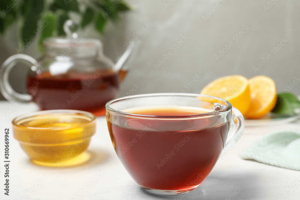 Delicious tea with honey and lemon on white table
