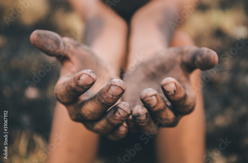 poor child or beggar begging you for help sitting at dirty slum. concept for poverty or hunger people,human rights,donate and charity for underprivileged children in third world  photo