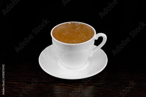 black coffee pour into a white mug on a dark background