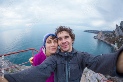 Loving couple takes a selfie on top of a cliff.
