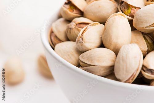 Bowl of roasted pistachios on a white background