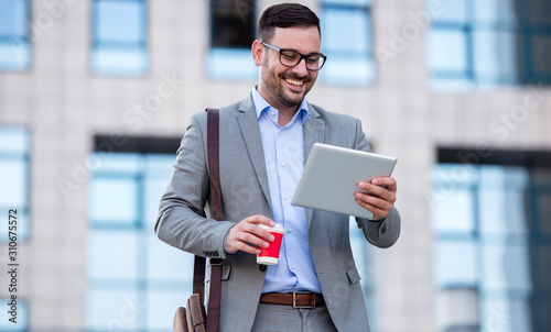 Businessman drinking coffee and checking notes with tablet. Business, lifestyle concept photo
