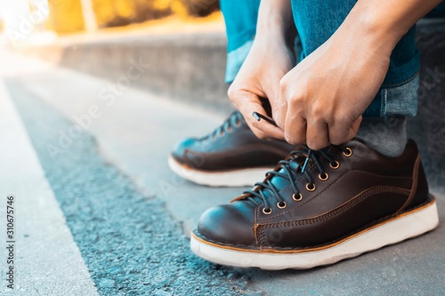 image of man is shoelace on wearing brown leather shoes 