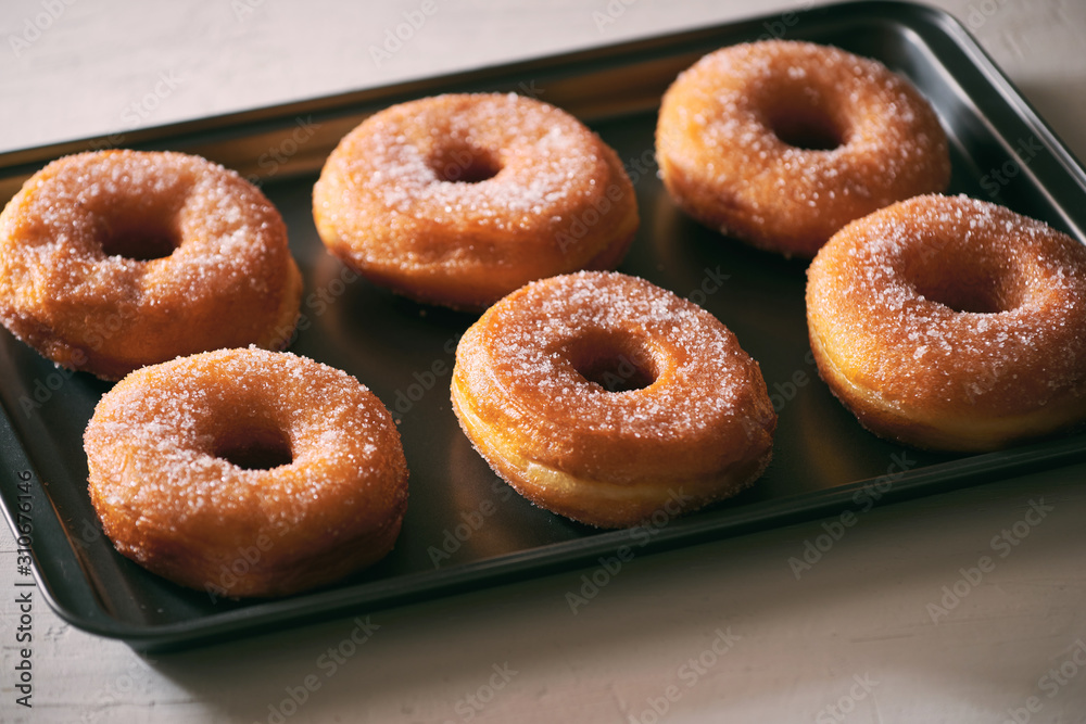Fried Donuts with Powdered Sugar on metal baking dish Fried Donuts with Powdered Sugar on metal baking dish