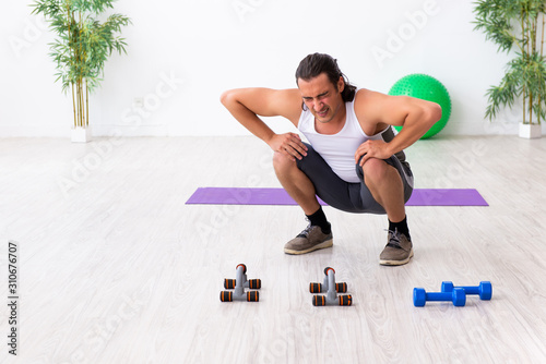 Young handsome man doing sport exercises indoors