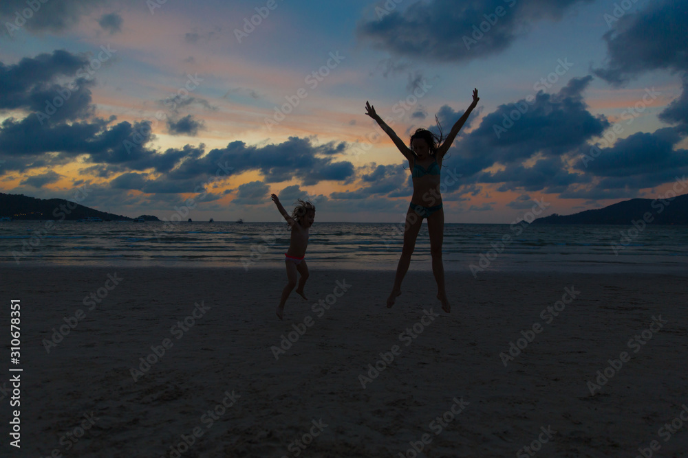 Mom and daughter play on the evening sea beach