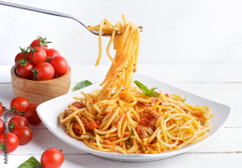 Delicious  spaghetti amatriciana sauceon a light concrete and tomato sauce on white plate