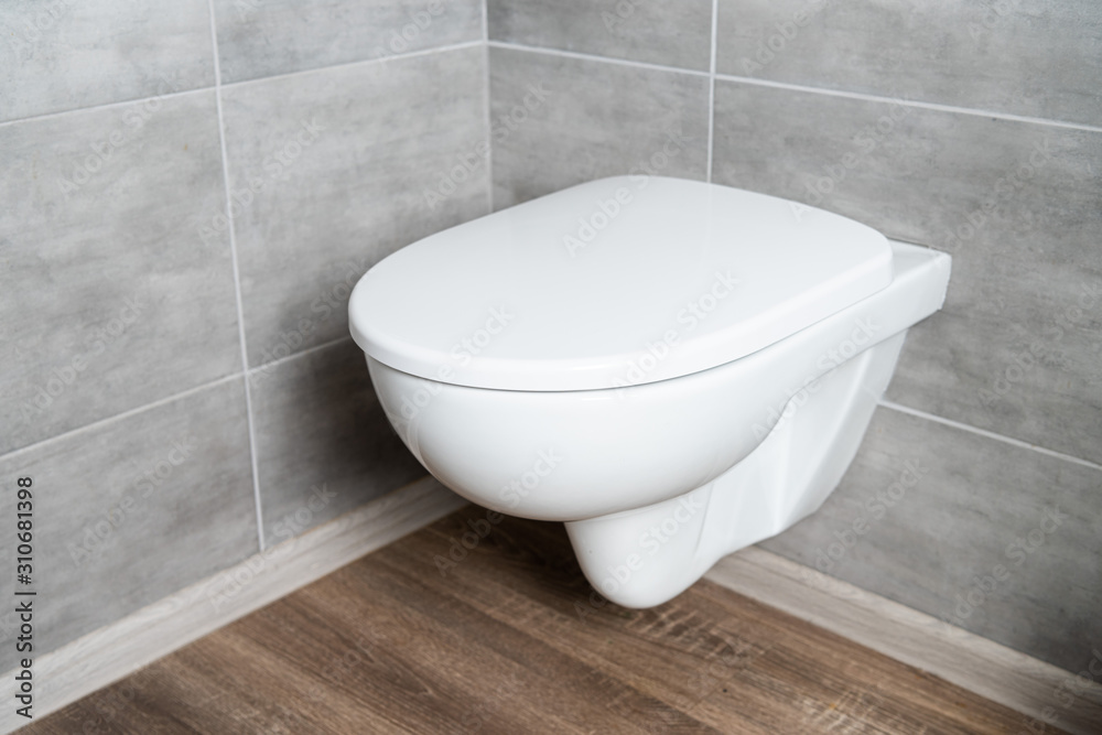 Clean white toilet bowl in restroom with grey tile Clean white toilet bowl in restroom with grey tile