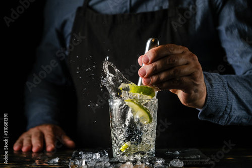 Bartender is preparing a refreshing cocktail with ice and lime. Bartender preparing Caipirinha cocktail. Summer cocktail at the nightclub.
