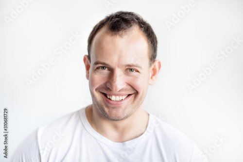 Closeup portrait of smiling 30 years old caucasian white man on white background in white t-shirt. Confident happy smart modern man. Lifestyle. Wide smile with healthy teeth.