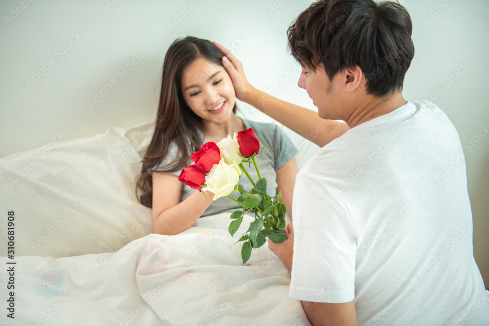 Asian young man surprise girl with roses on bed,husband encourage expected mom wife for pregnancy test,valentine day concept. Asian young man surprise girl with roses on bed,husband encourage expected mom wife for pregnancy test,valentine day concept.
