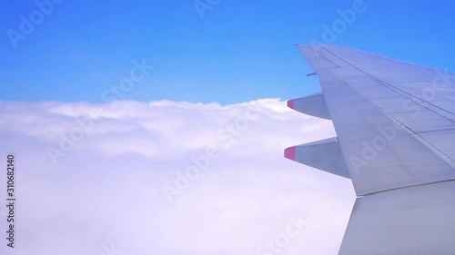 Wing of an airplane flying on the blue sky with fluffy clouds. Tourism transportation with vacation journey. Business and travel concept for add text or website.