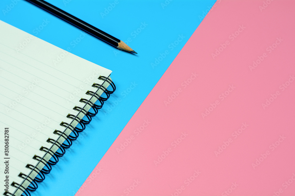 diary book and a pencil on blue and pink background with copy space. - top view. diary book and a pencil on blue and pink background with copy space. - top view.