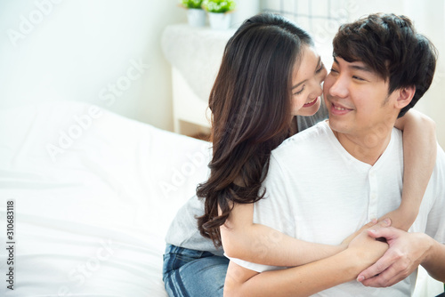Two young asian couple girl piggyback man from back on bed,romantic asia people in love hugging while sitting in bed,valentine day concept with copy space.