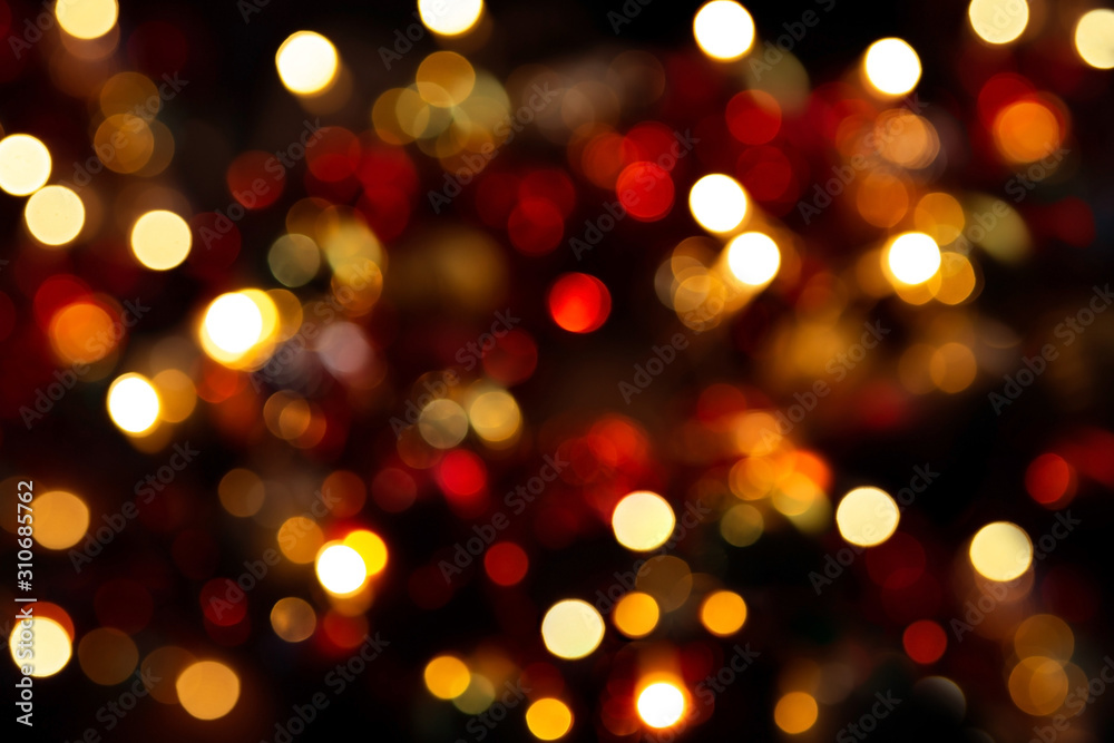 Bokeh in a circle on a dark background. Blurred christmas wreath. Abstract photograph. Yellow, red lights on a black background.