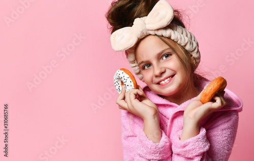 Beauty Fashion Model Girl is holding colorful donuts. Funny joyful girl in Vogue style with sweets on a pink background.