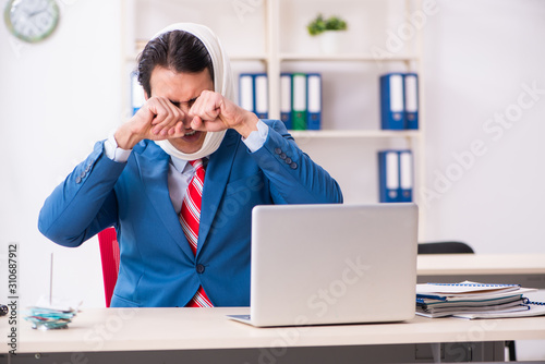 Young male employee suffering in the office