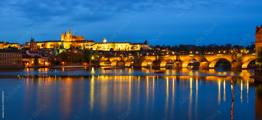 Prague skyline and bridge over river in night