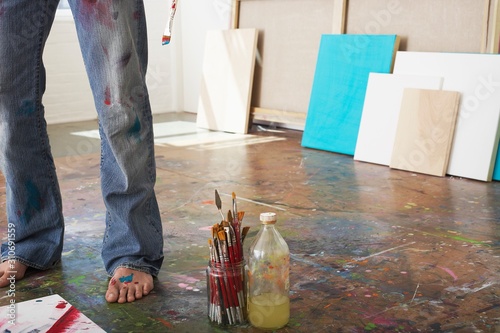 Artist's Legs By Brushes And Paint Thinner In Studio