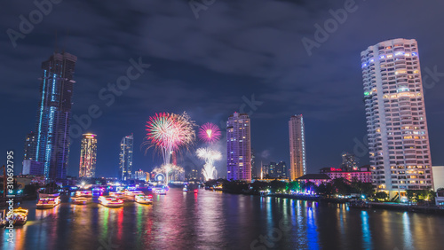 Fireworks on nre year countdown with the building the river around at Chaopraya river, Taksin bridge, Thailand.