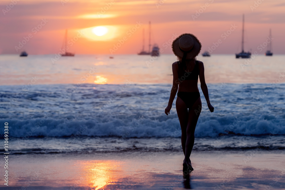 Silhouette of beautiful slim girl against sunset beach