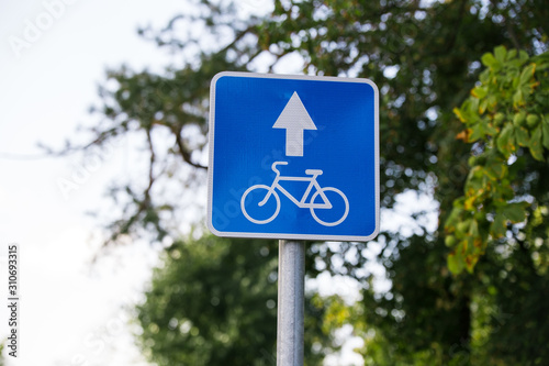 blue square road sign Lane for cyclists close - up on sky background with clouds, tree