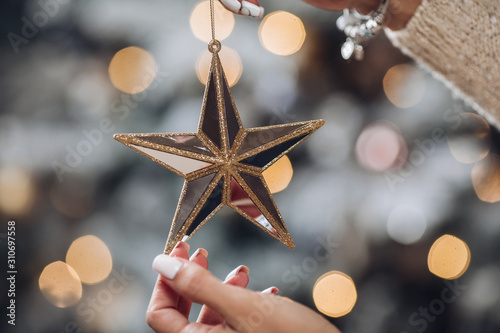 Close up of woman with toy glass decorative star in hands. New Year eve concept