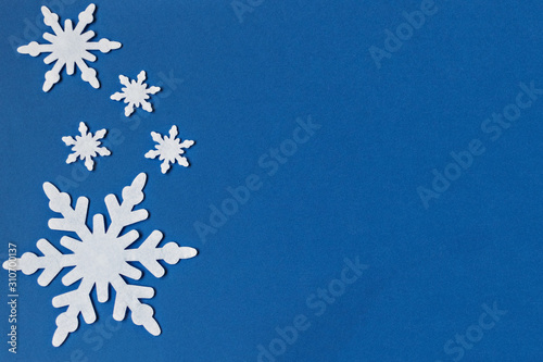 White felt snowflakes on a classic blue background. New Year card.