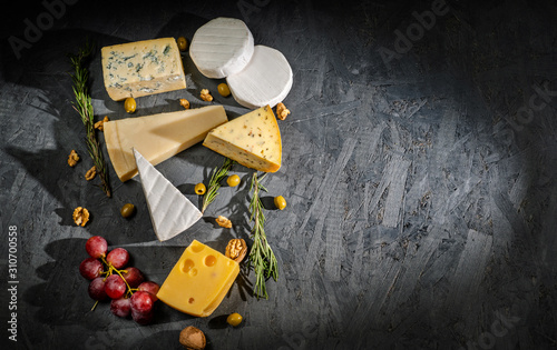 Different sorts of cheese. Cheese platter with different cheese, and spices on dark background. Top view, wiht copy space