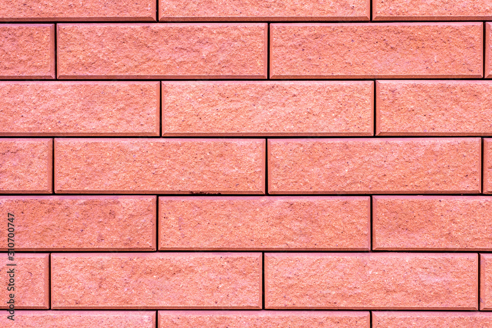 Creative pink background. Brick texture of unusual coral color.