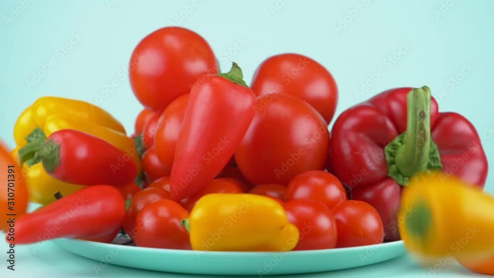 large and small bell peppers and tomatoes fall on the blue dish. blue background large and small bell peppers and tomatoes fall on the blue dish. blue background