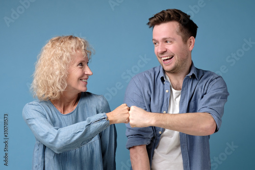 Happy smiling mature woman and man friends couple give bump looking at camera as partnership respect concept. Studio shot